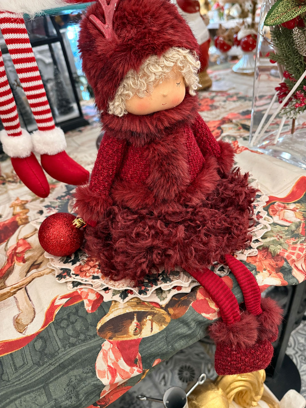 Poupée de Noël Demoiselle Bordeaux vue de trois quarts à gauche, tenue bordeaux et boule rouge en main