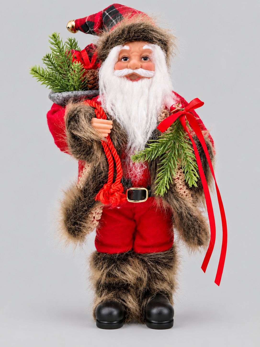 Poupée Père Noël Tradition en tenue rouge, avec bonnet écossais et sac garni, sur fond gris clair.