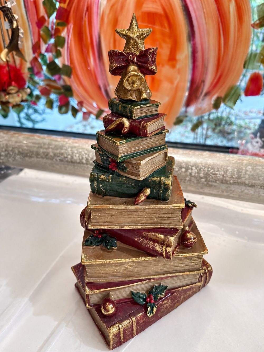 Figurine sapin de Noël composée de livres empilés rouges, verts et dorés, surmontée d’une étoile, décoration vintage et féérique à poser.