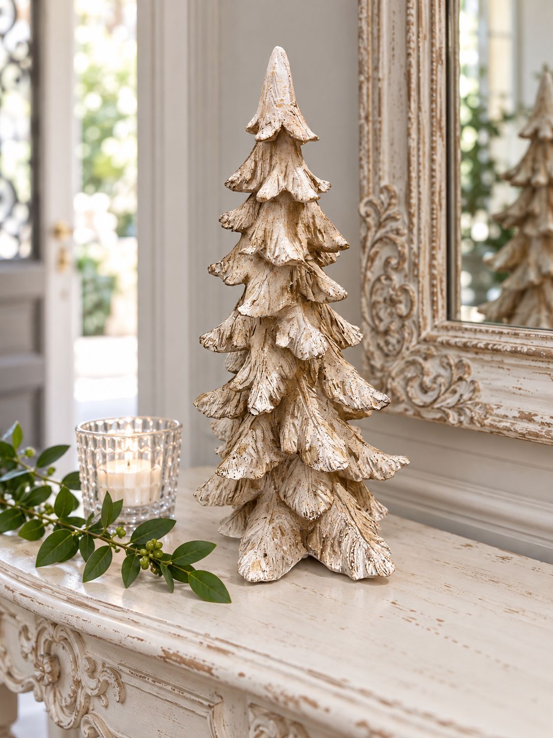 Sapin Roi des Neiges sur une console blanche patinée, près d’un miroir ancien et d’un photophore.
