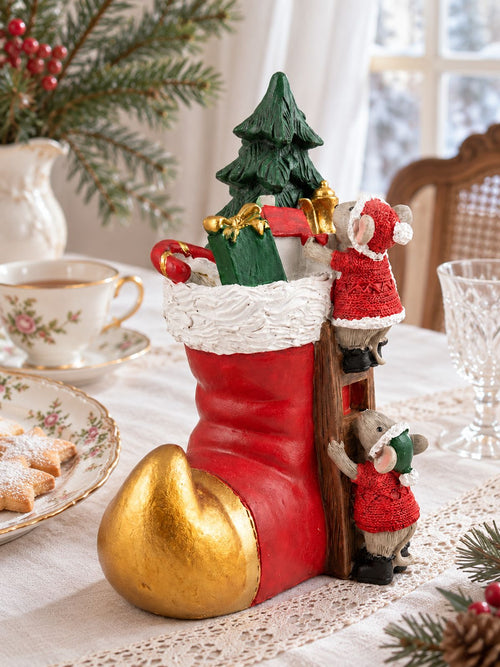 Soulier des Souris de Noël sur une table en lin et dentelle, accompagné de porcelaine fleurie et de biscuits étoilés.