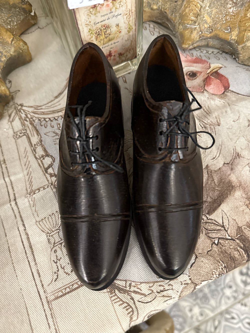 Paire de souliers décoratifs en métal noir patiné style ancien, posés sur un meuble de charme dans une ambiance vintage et romantique