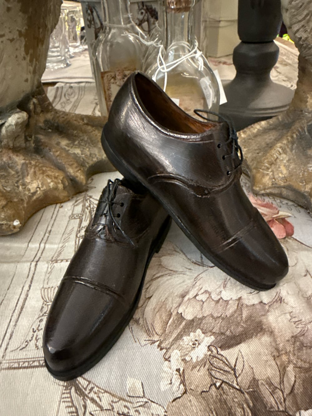 Paire de souliers décoratifs en métal noir patiné style ancien, posés sur un meuble de charme dans une ambiance vintage et romantique
