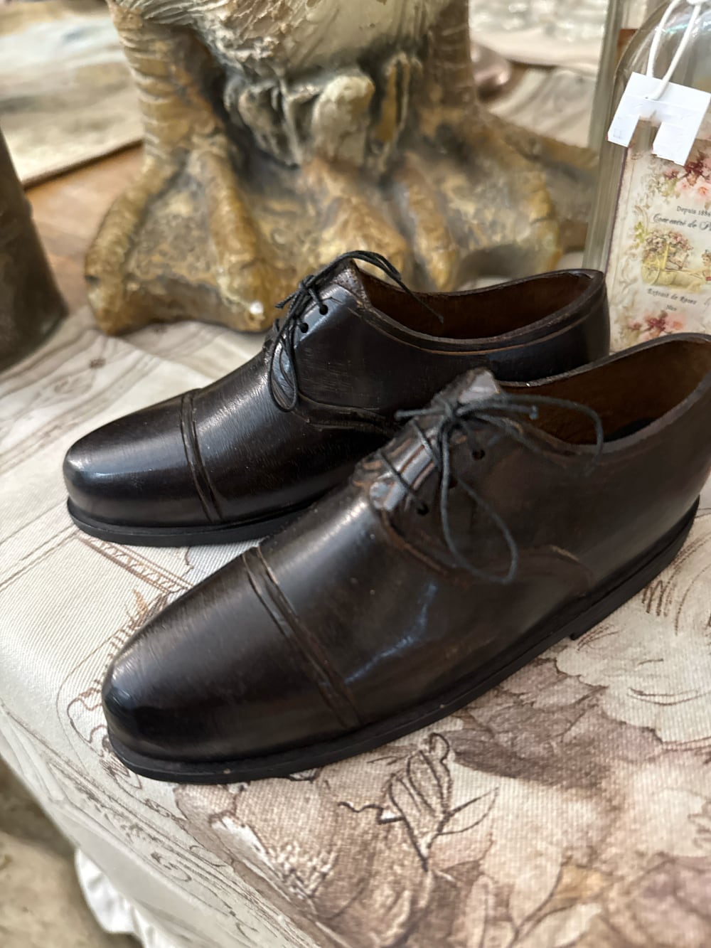 Paire de souliers décoratifs en métal noir patiné style ancien, posés sur un meuble de charme dans une ambiance vintage et romantique