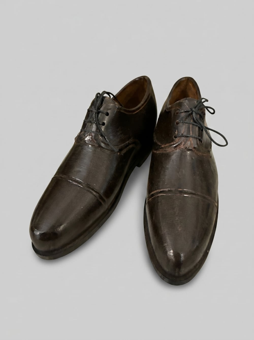 Paire de souliers décoratifs en métal noir patiné style ancien, posés sur un meuble de charme dans une ambiance vintage et romantique