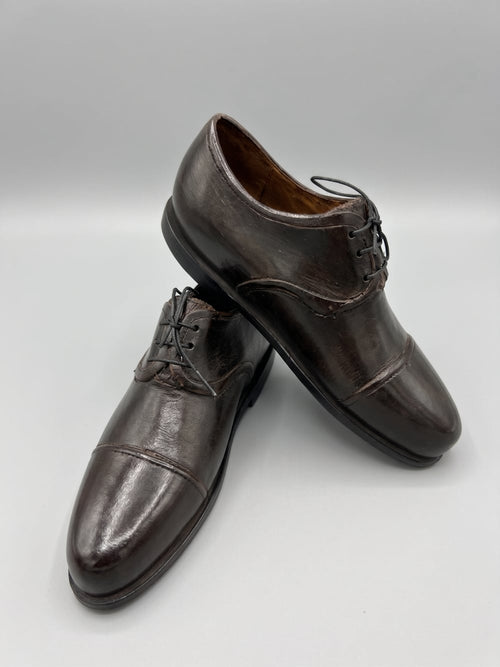 Paire de souliers décoratifs en métal noir patiné style ancien, posés sur un meuble de charme dans une ambiance vintage et romantique