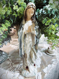 Statuette décorative de la Vierge Marie en prière tenant un chapelet doré, finitions nacrées blanc cassé, détails roses à la base, style romantique et shabby chic, ambiance spirituelle et poétique