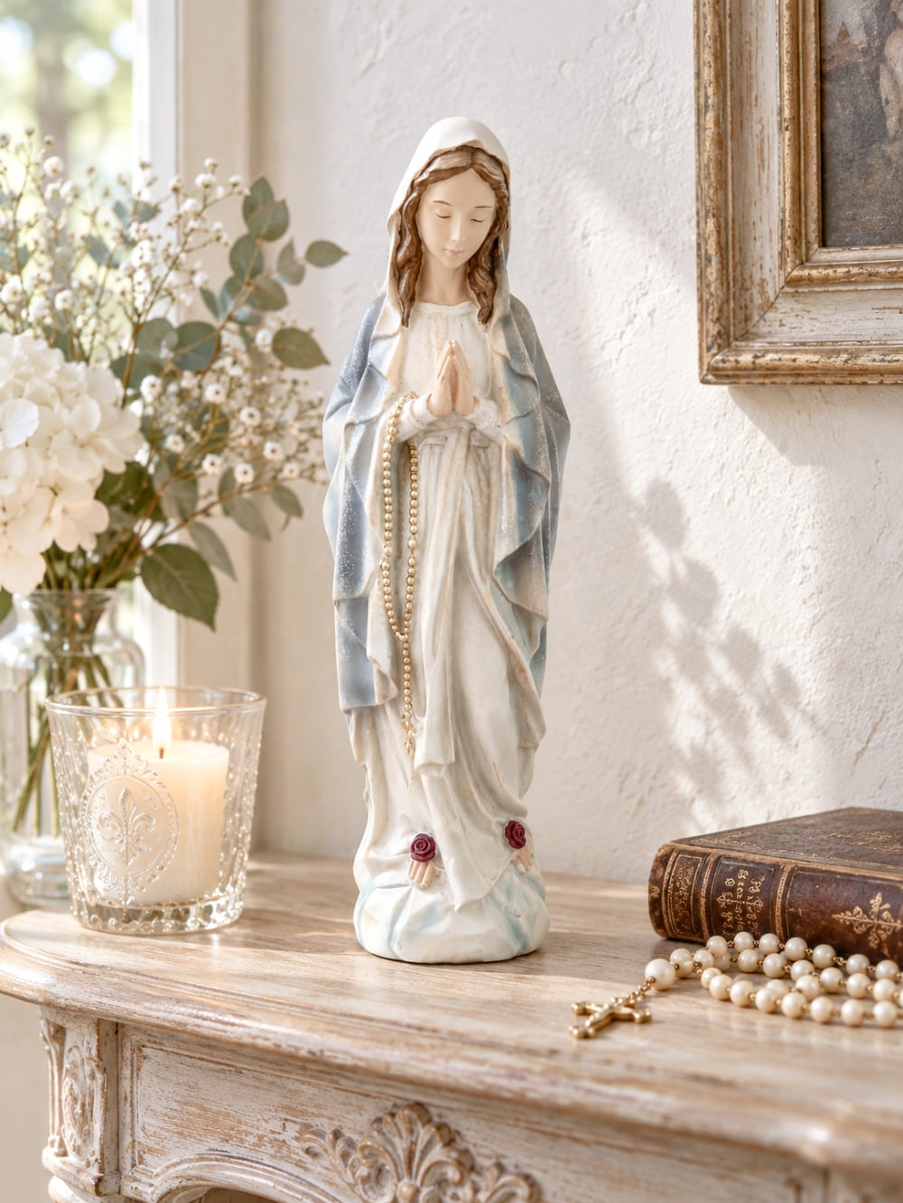 Statuette décorative de la Vierge Marie en prière tenant un chapelet doré, finitions nacrées blanc cassé, détails roses à la base, style romantique et shabby chic, ambiance spirituelle et poétique