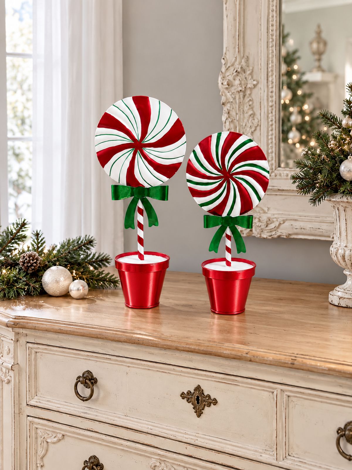 Deux sucettes décoratives de Noël rouge, blanc et vert sur une commode ancienne dans un intérieur lumineux.