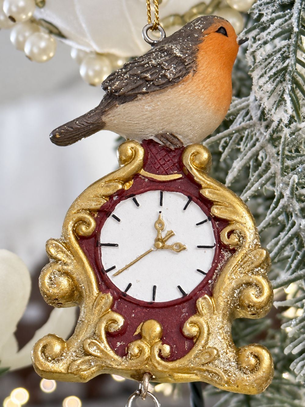 Gros plan du rouge-gorge et du cadran blanc de l’horloge aux ornements dorés.