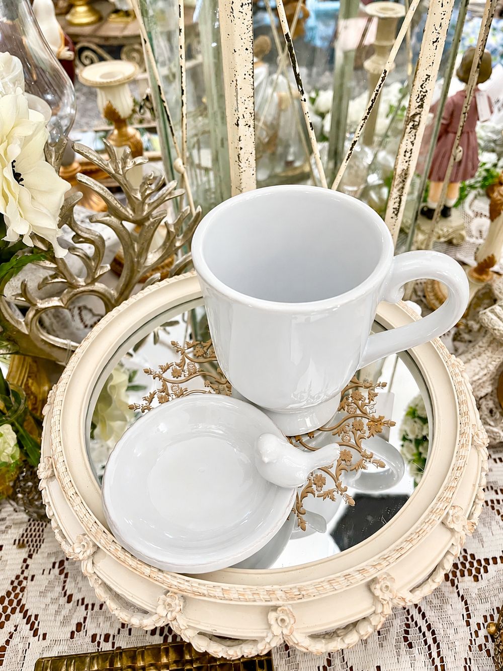 Vue de dessus de la tasse blanche et de sa coupelle ornée d’un oiseau.