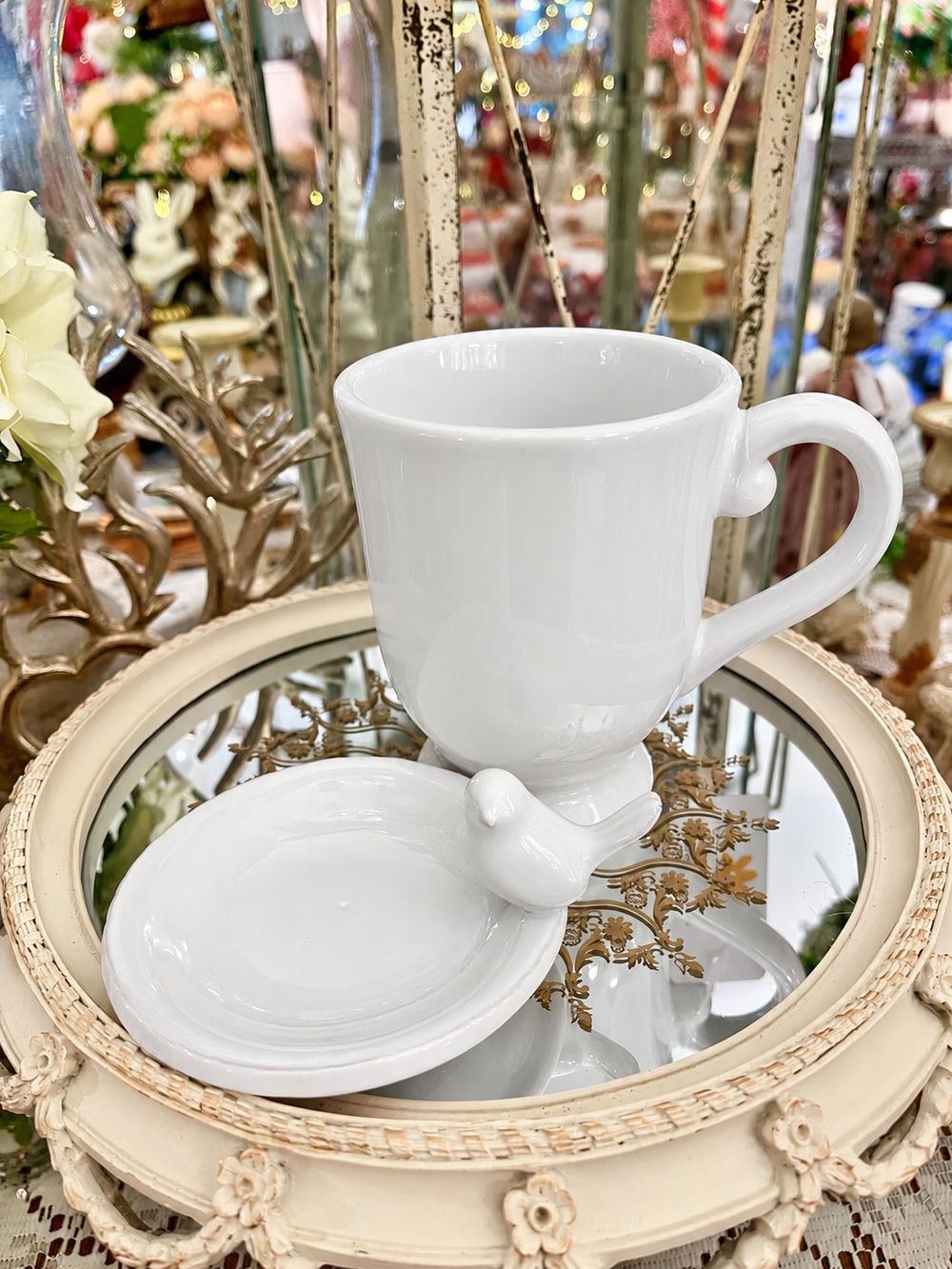Tasse Chant de l’Oiseau en faïence blanche avec sa coupelle à côté, vue de face.