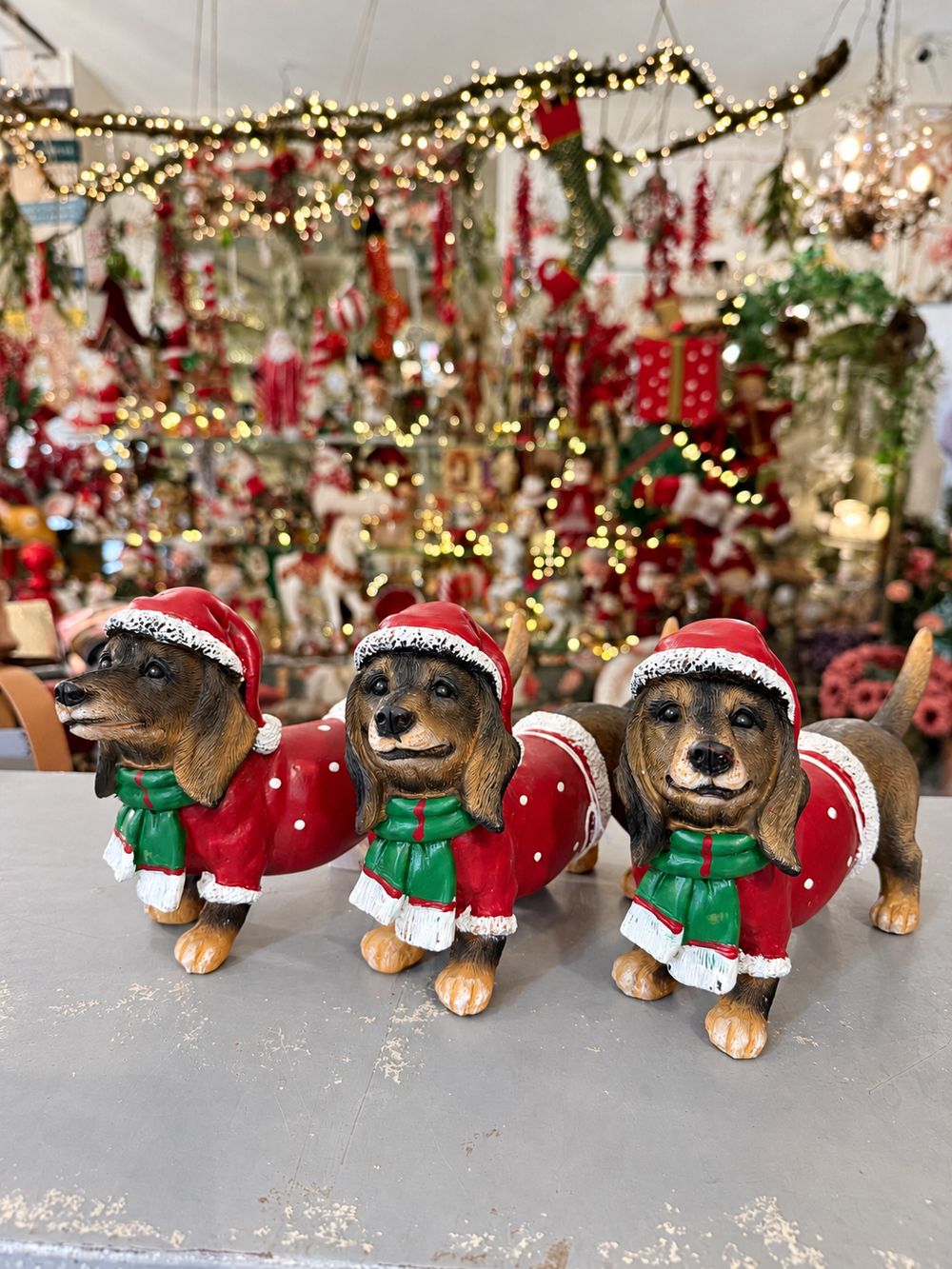 Trois figurines Teckel des Neiges en tenue de Noël.