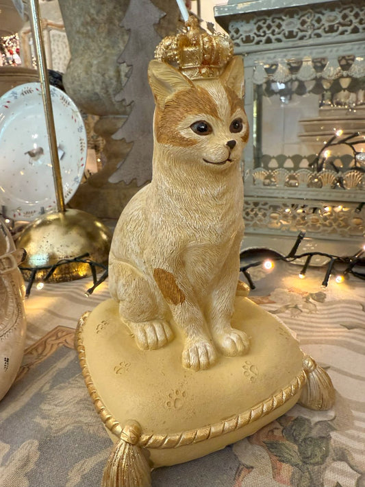 Tirelire décorative en forme de chat couronné, couleurs beige, doré et marron, style shabby chic romantique et poétique, posée sur un coussin élégant