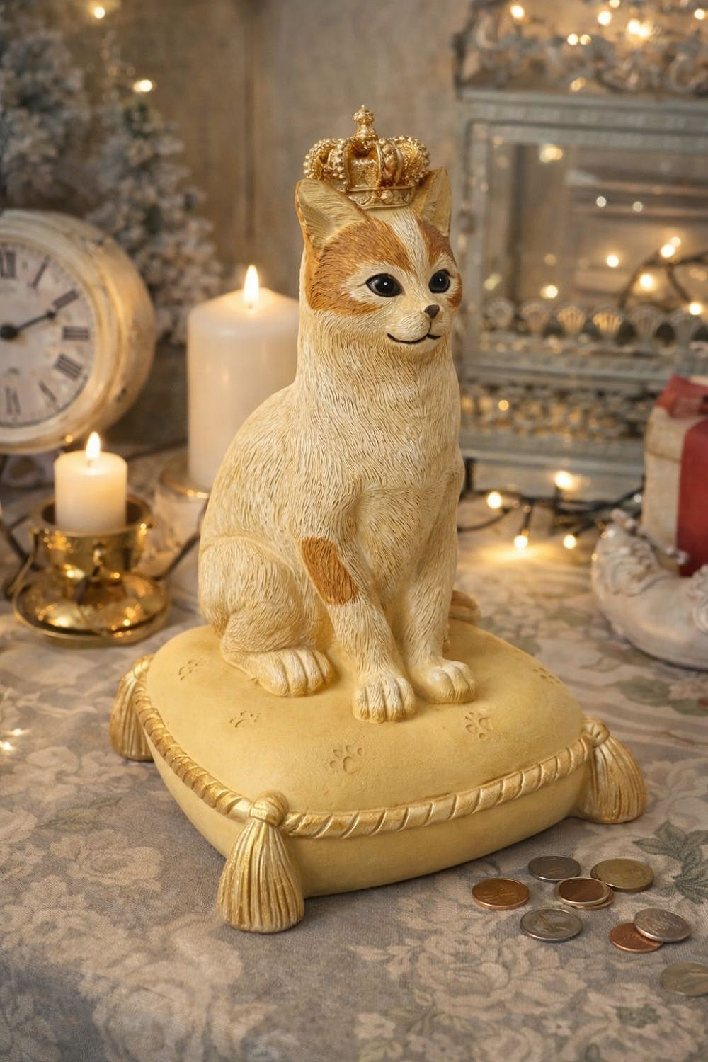 Tirelire décorative en forme de chat couronné, couleurs beige, doré et marron, style shabby chic romantique et poétique, posée sur un coussin élégant