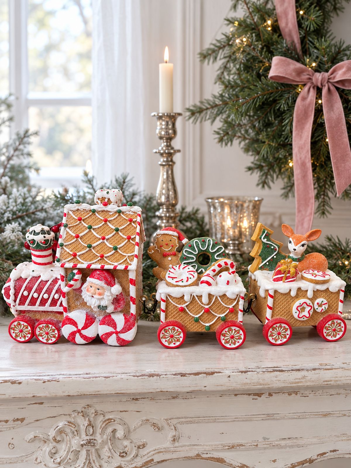 Train Enchanté du Père Noël sur une console blanche patinée, près d’une couronne de sapin au ruban rose.