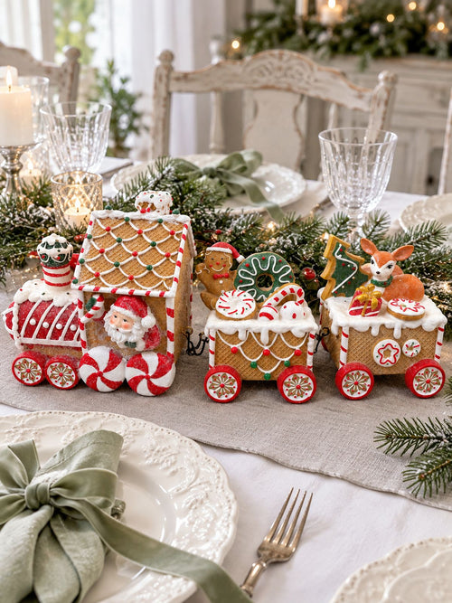 Train Enchanté du Père Noël en centre de table, entouré de vaisselle blanche et de serviettes vert sauge.