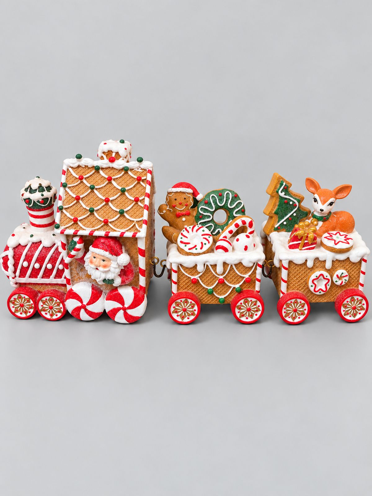 Train Enchanté du Père Noël et ses deux wagons décoratifs aux motifs de pain d’épices, sur fond gris clair.